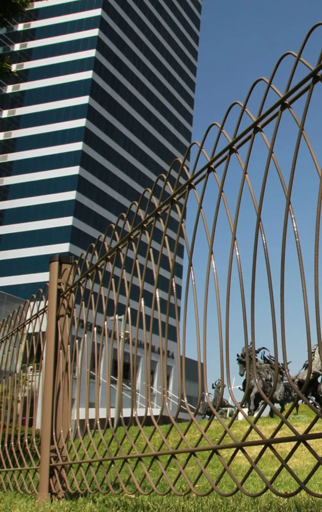 Reja ornamental de alambre continuo con remates curvos en el cerramiento de un edificio corporativo