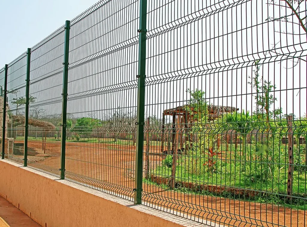 Reja de seguridad galvanizada verde con pliegues en V instalada como cerramiento perimetral sobre muro
